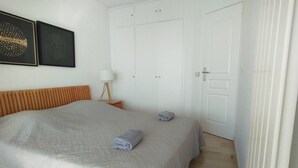A bedroom with a bed, a nightstand, a lamp, and a wardrobe. - Incredible ocean view, pool, HVAC, Wi-Fi, sleeps 4 (Vallauris)