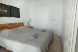 Ein Schlafzimmer mit einem Bett, einem Nachttisch, einer Lampe und einem Kleiderschrank.