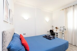 A bedroom with a bed, pillows, a desk with a lamp, and a fan. - Home2Book Bright Stay in Los Abrigos (Los Abrigos)