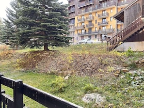 A residential building with balconies, a tree, and a grassy area with rocks. - 50m from ski slopes, Ground floor, balcony, tv, ski locker, 26m², Risoul (Risoul)