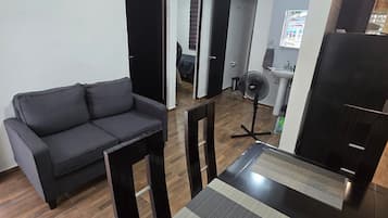 Uma sala de estar moderna com um sofá, uma mesa de jantar com cadeiras, um ventilador e um rack para TV.