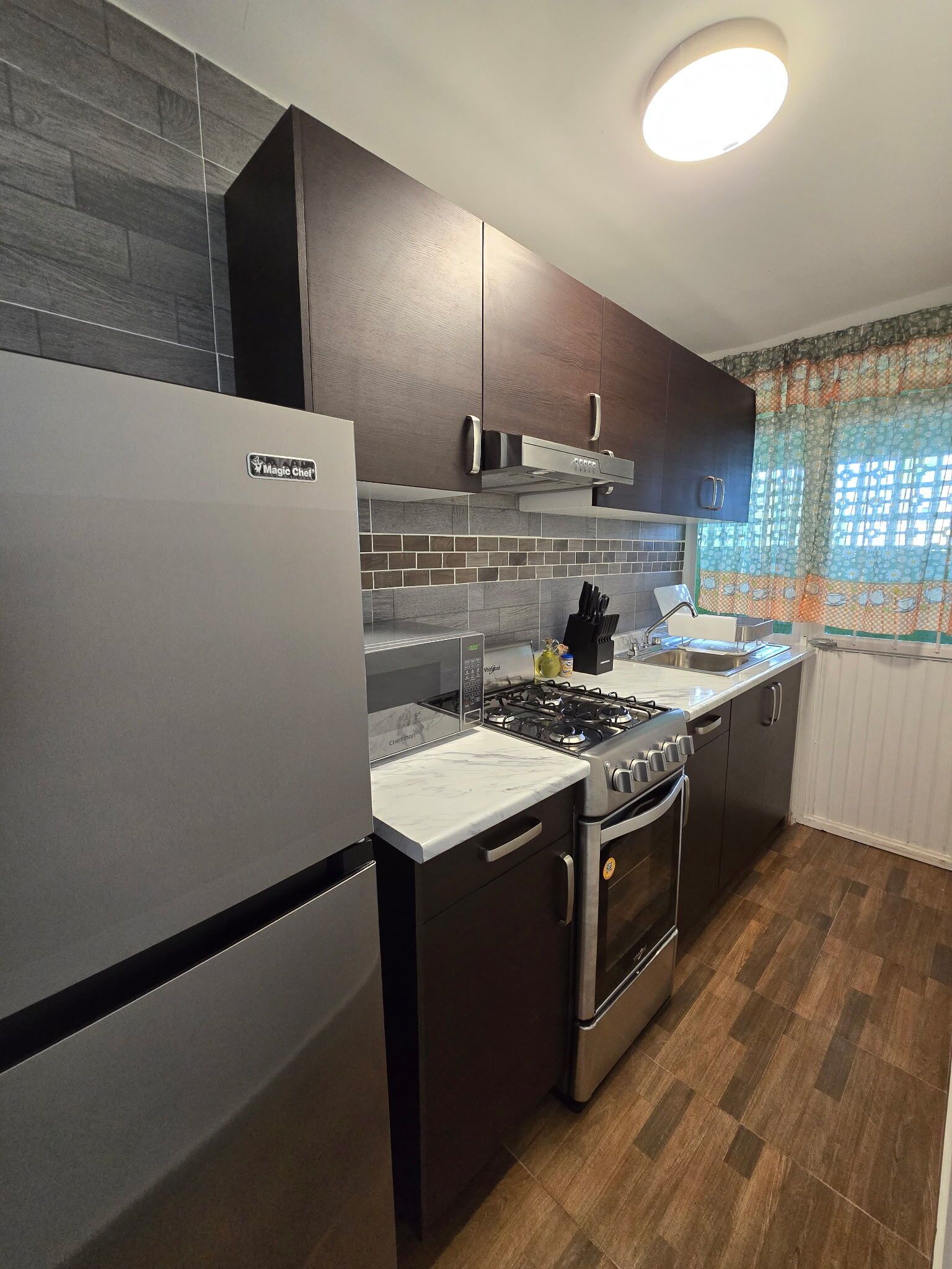 A kitchen with a refrigerator, stove, oven, and microwave.
