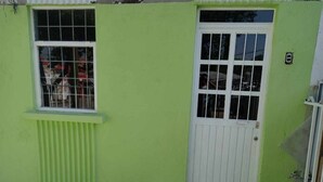 A building with a green exterior, a white door, and a window with metal bars.