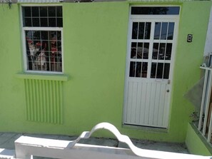 A building with a green exterior, a white door, and a window with metal bars.