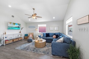 A modern living room with a blue sofa, a round coffee table, and a ceiling fan.