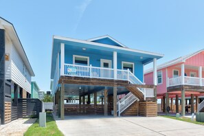 A beachfront property with a blue building featuring a balcony and a wooden deck.