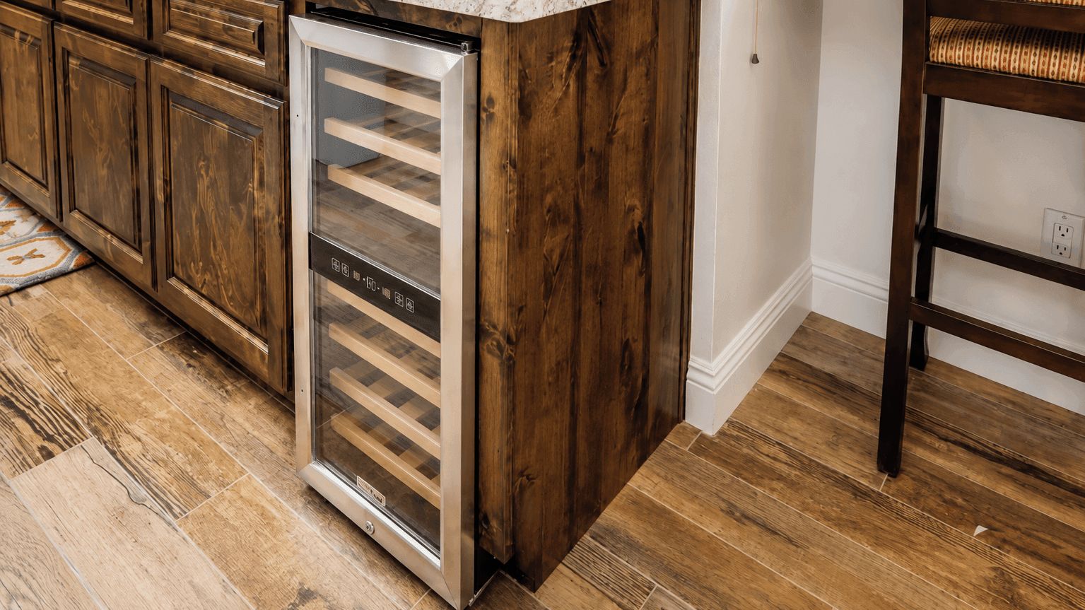Una cocina con armarios de madera, un electrodoméstico de acero inoxidable y un tapete estampado.