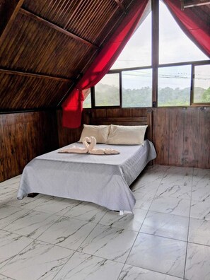A room with a bed, a window, and a view of the outdoors.
