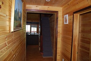 A wooden interior hallway with a staircase leading to a room with a window.