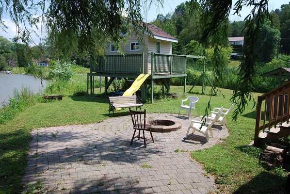 A playground with a slide, a bench, and a fire pit area.