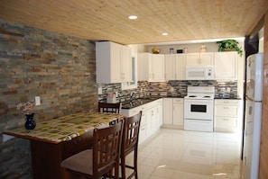 A kitchen with white cabinets, a black countertop, and a tiled backsplash.