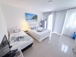 Habitación de hotel con dos camas, un cuadro de una playa, un televisor y un dispensador de agua.