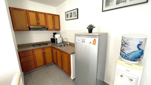 Una cocina con gabinetes de madera, un refrigerador de acero inoxidable, un microondas y un fregadero.