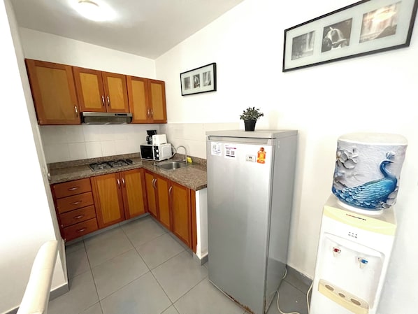 A kitchen with wooden cabinets, a stainless steel refrigerator, a microwave, and a sink. - Tropical Adventure STUDIOS HOTEL & SPA (Punta Cana)