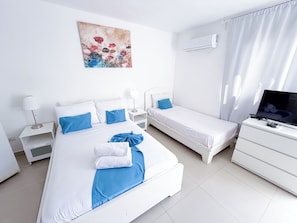 A hotel room with a large bed, a smaller bed, a TV, and a painting on the wall. - Tropical Adventure STUDIOS HOTEL & SPA (Punta Cana)