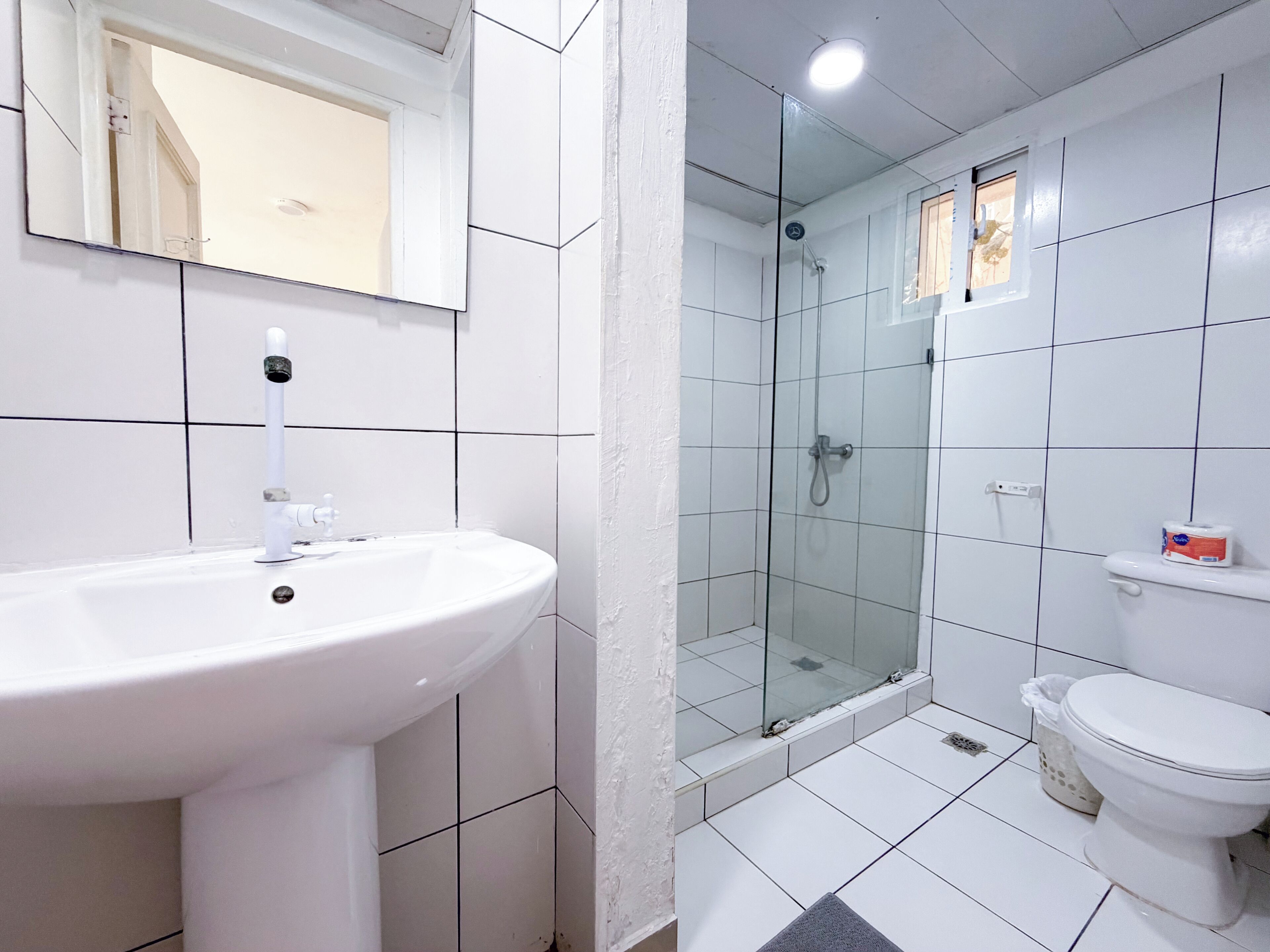 Ein Badezimmer mit einem weißen Waschbecken, einer Duschkabine aus Glas und einer Toilette.