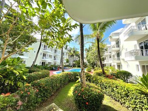 Un hotel con varios balcones, piscina y abundante vegetación.