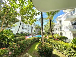 Un hotel con varios balcones, piscina y abundante vegetación.