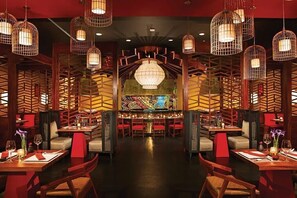 A restaurant with multiple dining tables, chairs, and hanging light fixtures.