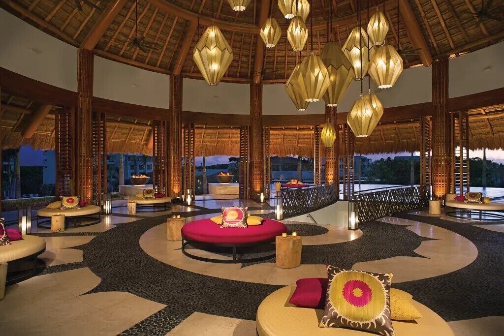 A spacious lobby with a circular seating area, a thatched roof ceiling, and a view of the outdoors.