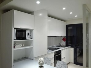 A modern kitchen with white cabinetry, a microwave, a sink, and an oven. - Modern Apartment with Pool View—Castillo Caleta de Fuste (Castillo Caleta de Fuste)