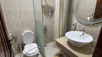 A bathroom with a glass-enclosed shower, a white toilet, a sink with a mirror, and a shower curtain.