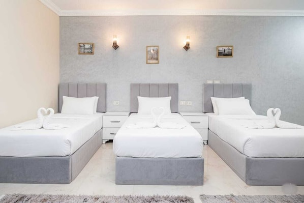 A hotel room with three beds arranged in a row, each with a matching headboard and footboard. - Luxury Gem view Facing tde Grand Egyptian Museum (Giza Governorate)