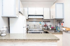 A kitchen with white cabinets, a gas stove, a sink, and various kitchen utensils. - Luxury Gem view Facing tde Grand Egyptian Museum (Giza Governorate)