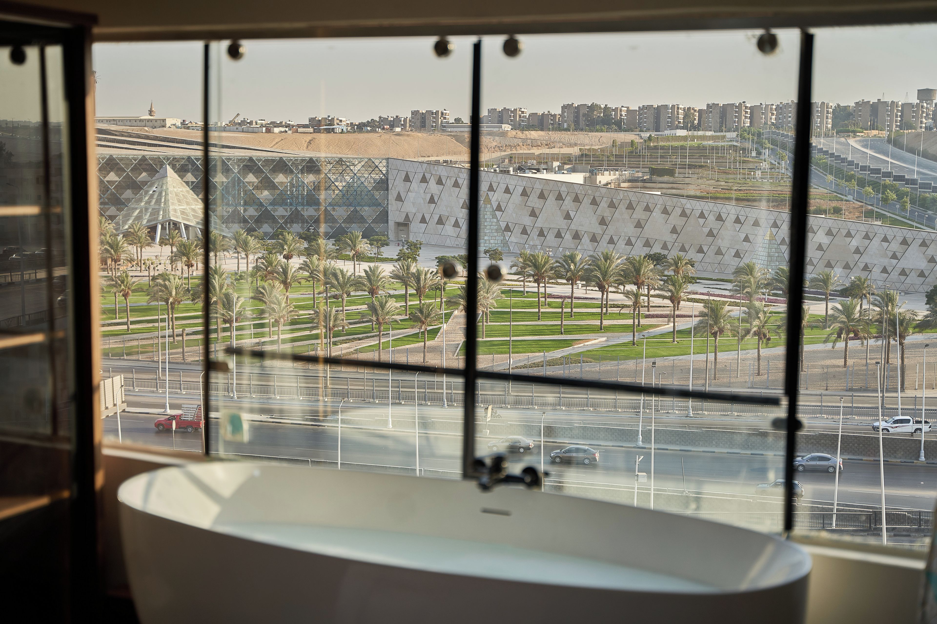 A modern bathroom with a large bathtub and a view of a cityscape through a window.