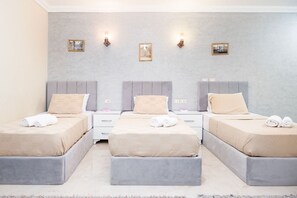 A hotel room with three beds, each with a pillow and a rolled towel. There are wall-mounted lights and framed pictures on the wall. - Luxury Gem view Facing tde Grand Egyptian Museum (Giza Governorate)