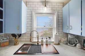 Una cocina con ventana, un lavabo y armarios.