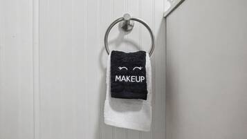 Une serviette ornée d’un motif de maquillage, suspendue à un anneau métallique.