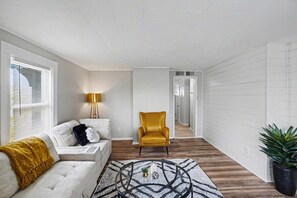 Un salon avec un canapé, un fauteuil jaune, une lampe et une table basse.