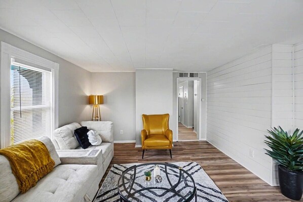 A living room with a sofa, a yellow armchair, a lamp, and a coffee table.