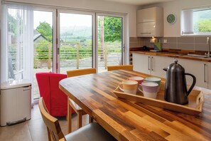 A modern kitchen with a wooden table, chairs, and a coffee pot. - Hawthorn Brae - A Peaceful Highland Retreat (Pitlochry)