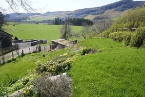 Un paysage rural avec un pont de pierre, des champs verdoyants et une ferme.