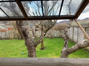A view through a skylight of a grassy yard with trees and a wooden fence. - Hawthorn Brae - A Peaceful Highland Retreat (Pitlochry)