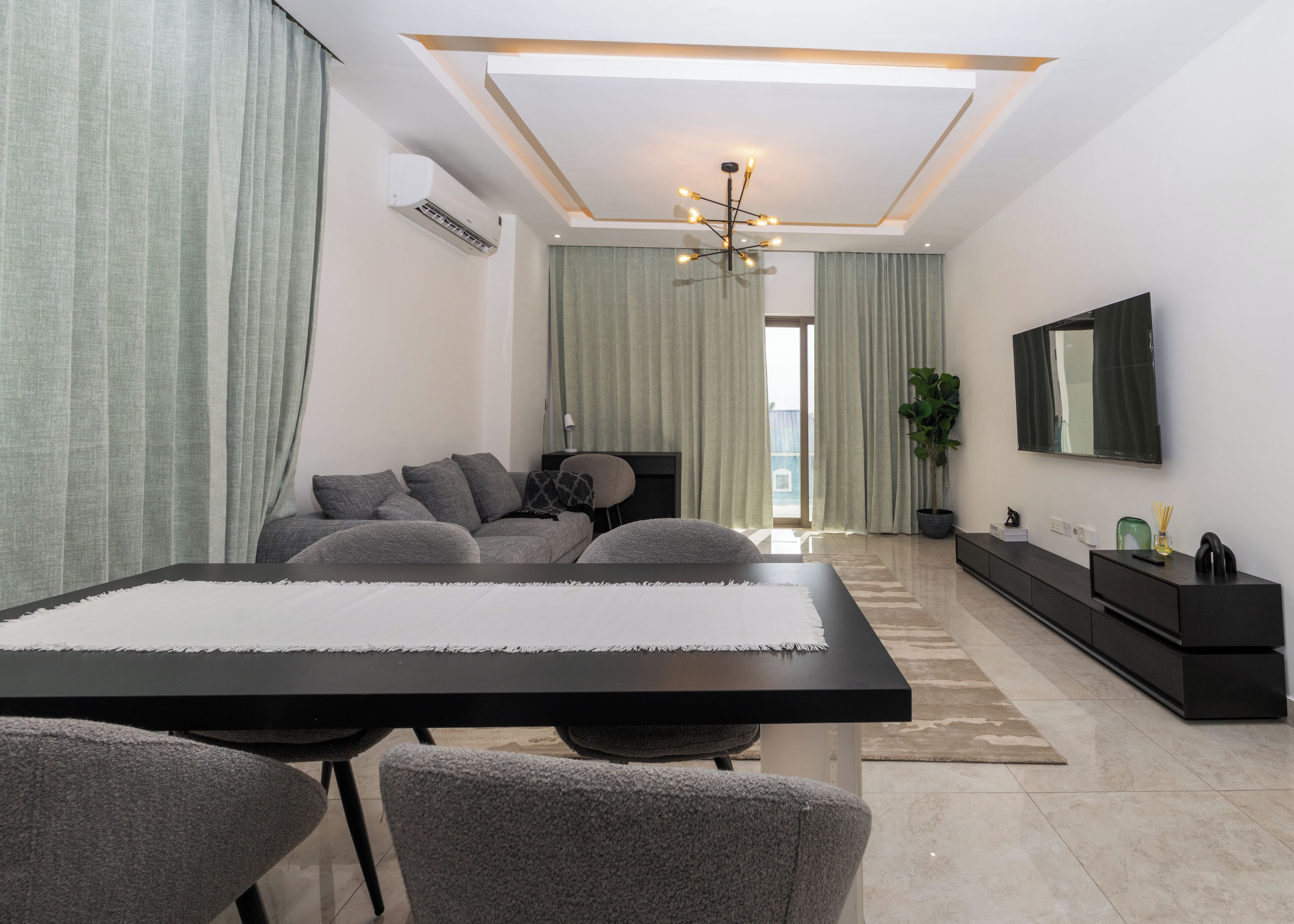 Uma sala de estar moderna com um sofá, uma mesa de jantar e uma televisão.