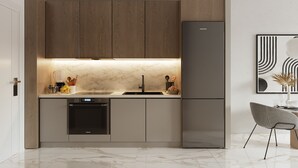 Una cocina moderna con lavavajillas integrado, un refrigerador y un comedor con una silla y mesa.