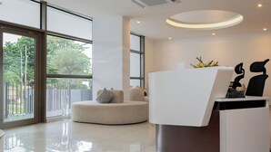 Una moderna zona de recepción con un escritorio blanco, un espacio de asientos circular y grandes ventanales con vistas al exterior.