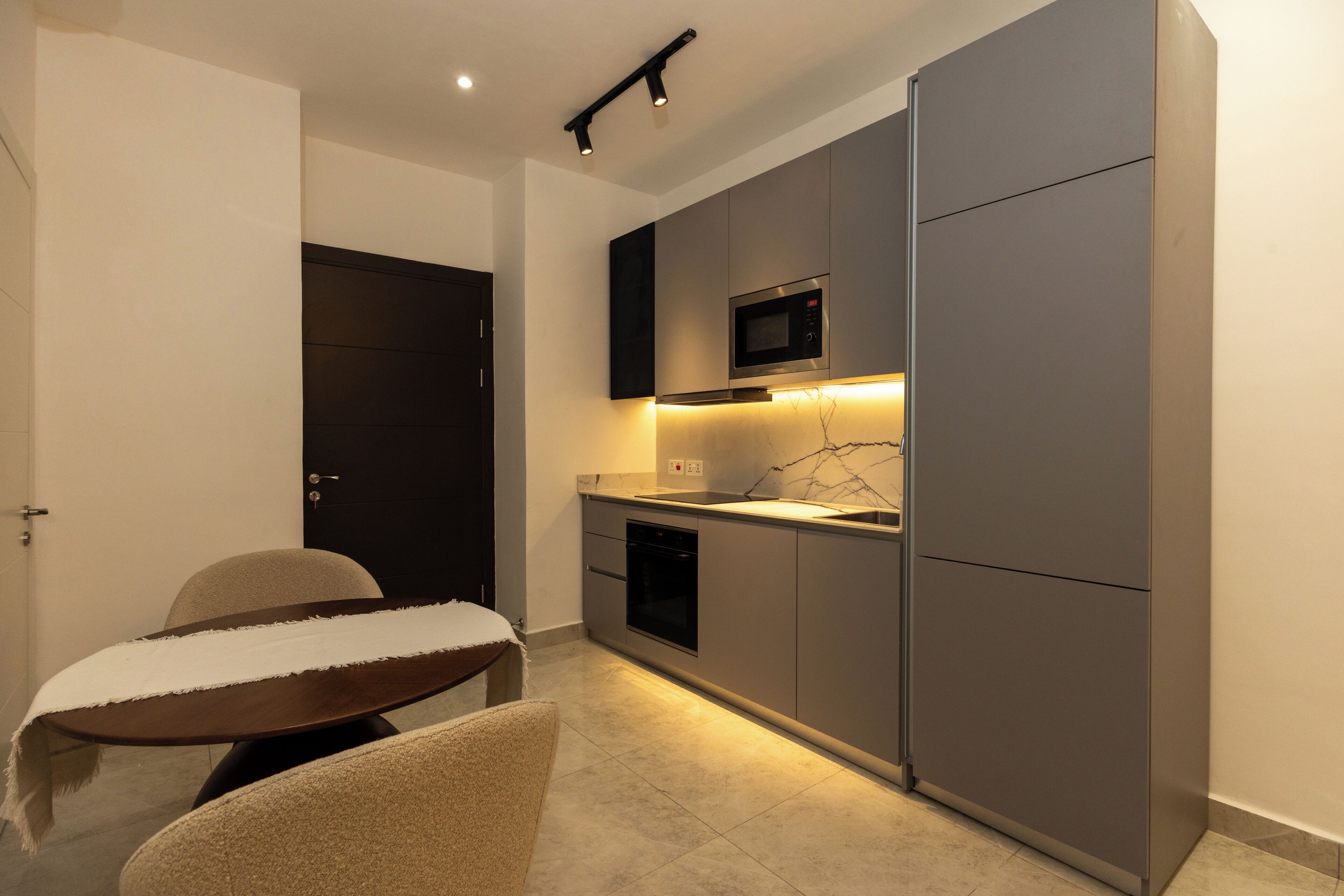 A compact kitchen with a built-in microwave, oven, and a small dining area with a table and chairs.