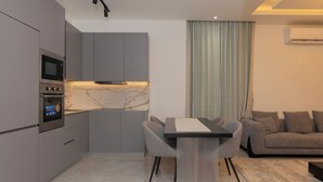 Una cocina moderna con electrodomésticos integrados, encimera de mármol y comedor con mesa y sillas.