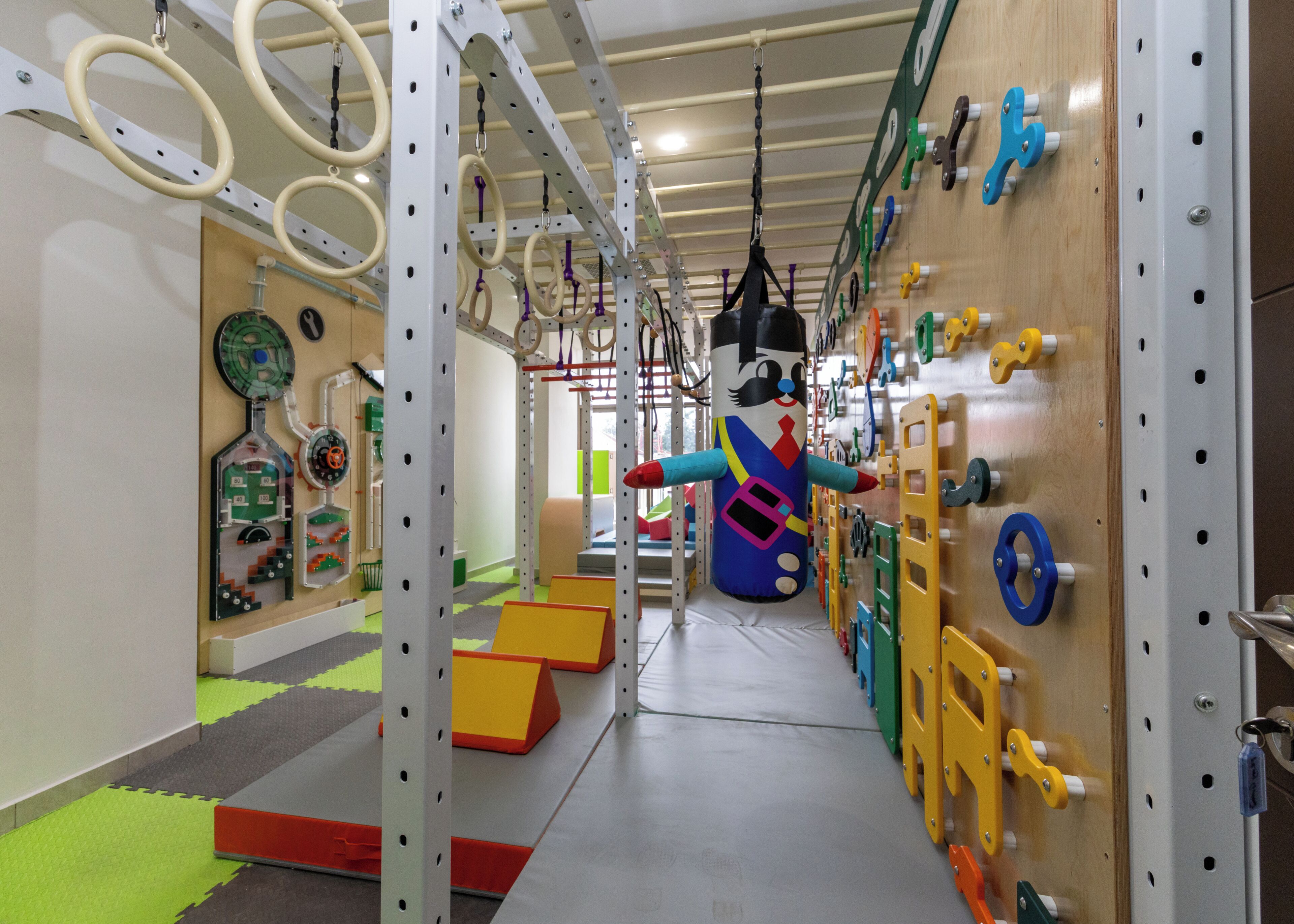 Ein Fitnessstudio mit verschiedenen Trainingsgeräten, darunter Ringen, einem Sandsack und einer Kletterwand.