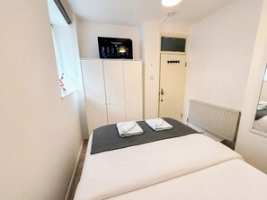 A hotel room with a bed, a wardrobe, a control panel, and a radiator. - Cosy Double Room near Aldgate East & Brick Lane (London)