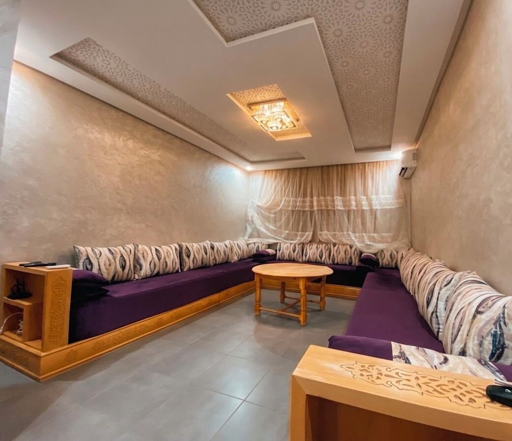 A modern living room with a sectional sofa, a small wooden table, and a decorative ceiling light.