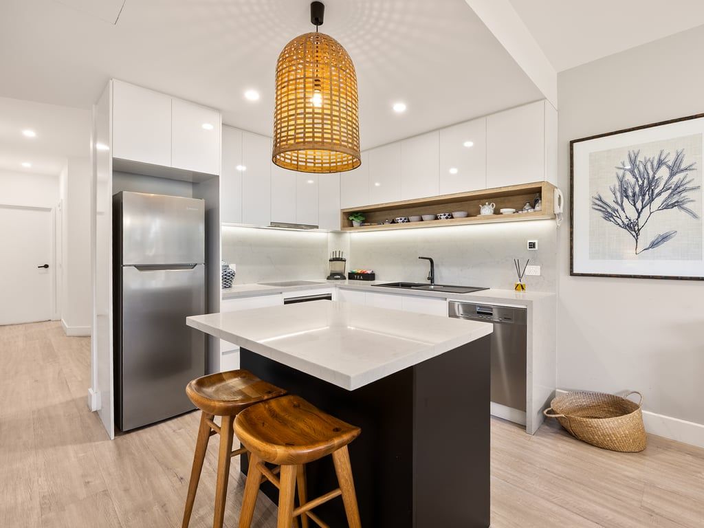 A modern kitchen with a central island, stainless steel appliances, and a hanging light fixture.