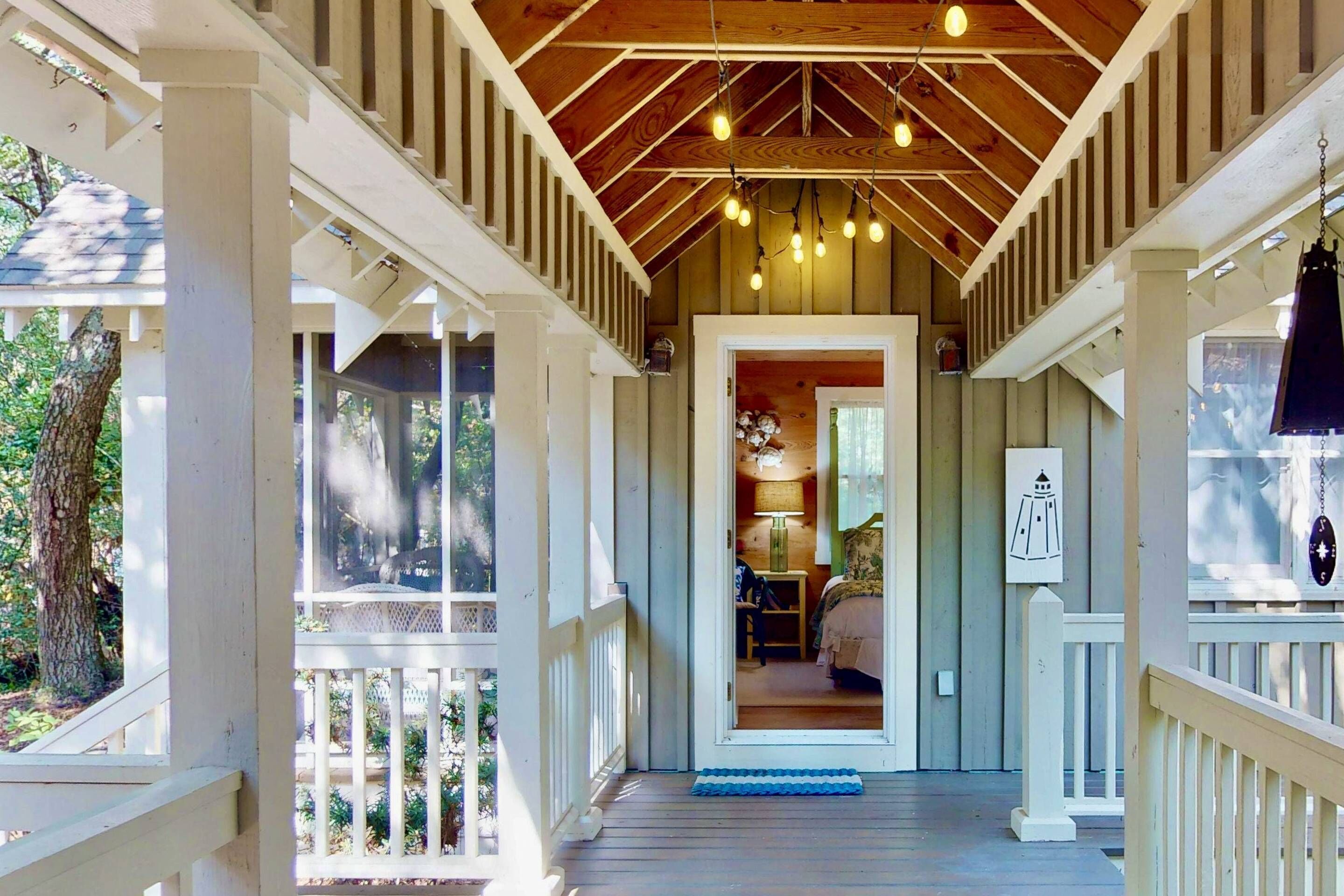 Une véranda couverte avec un plafond en bois et des balustrades blanches.