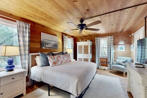 A cozy bedroom with a bed, nightstands, a dresser, a television, and a ceiling fan. - 2 Private Wings, Great Outdoor Spaces, Secluded Maritime Forest, Dogs OK, BHI Club + Golf (Bald Head Island)