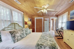 A wooden cabin interior with a bed, desk, and a television. - 2 Private Wings, Great Outdoor Spaces, Secluded Maritime Forest, Dogs OK, BHI Club + Golf (Bald Head Island)