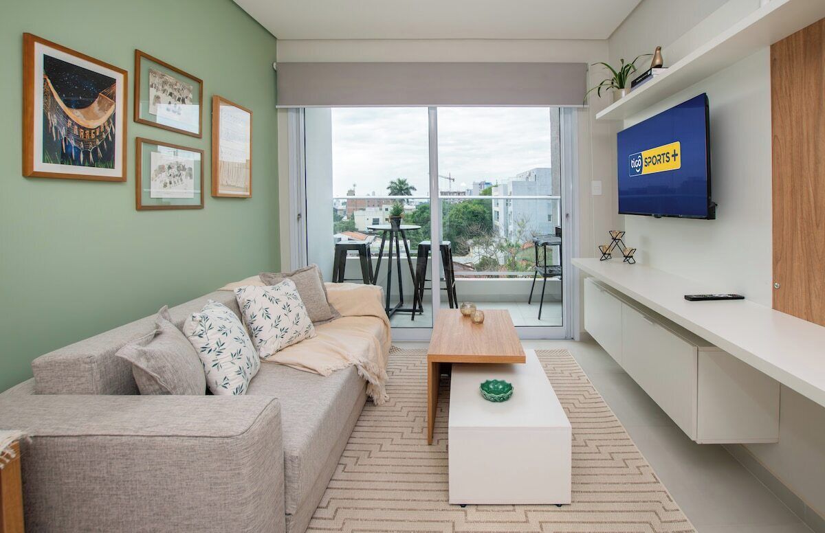 A modern living room with a sofa, coffee table, and a TV mounted on the wall.